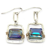 A pair of sterling silver box earrings with ocean blue crystal tiles wrapped in gold filled wire, hanging from a textured sterling silver link