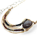 A satiny mauve moonstone necklace with bronze waves and tourmaline micro faceted gemstones, featuring a gold filled chain and a sterling silver signature clasp.