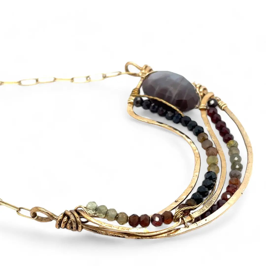 A satiny mauve moonstone necklace with bronze waves and tourmaline micro faceted gemstones, featuring a gold filled chain and a sterling silver signature clasp.