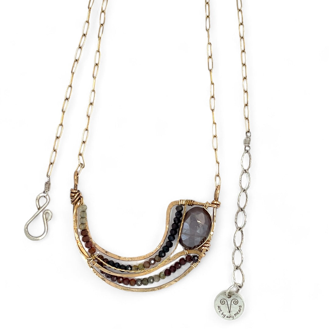 A satiny mauve moonstone necklace with bronze waves and tourmaline micro faceted gemstones, featuring a gold filled chain and a sterling silver signature clasp.