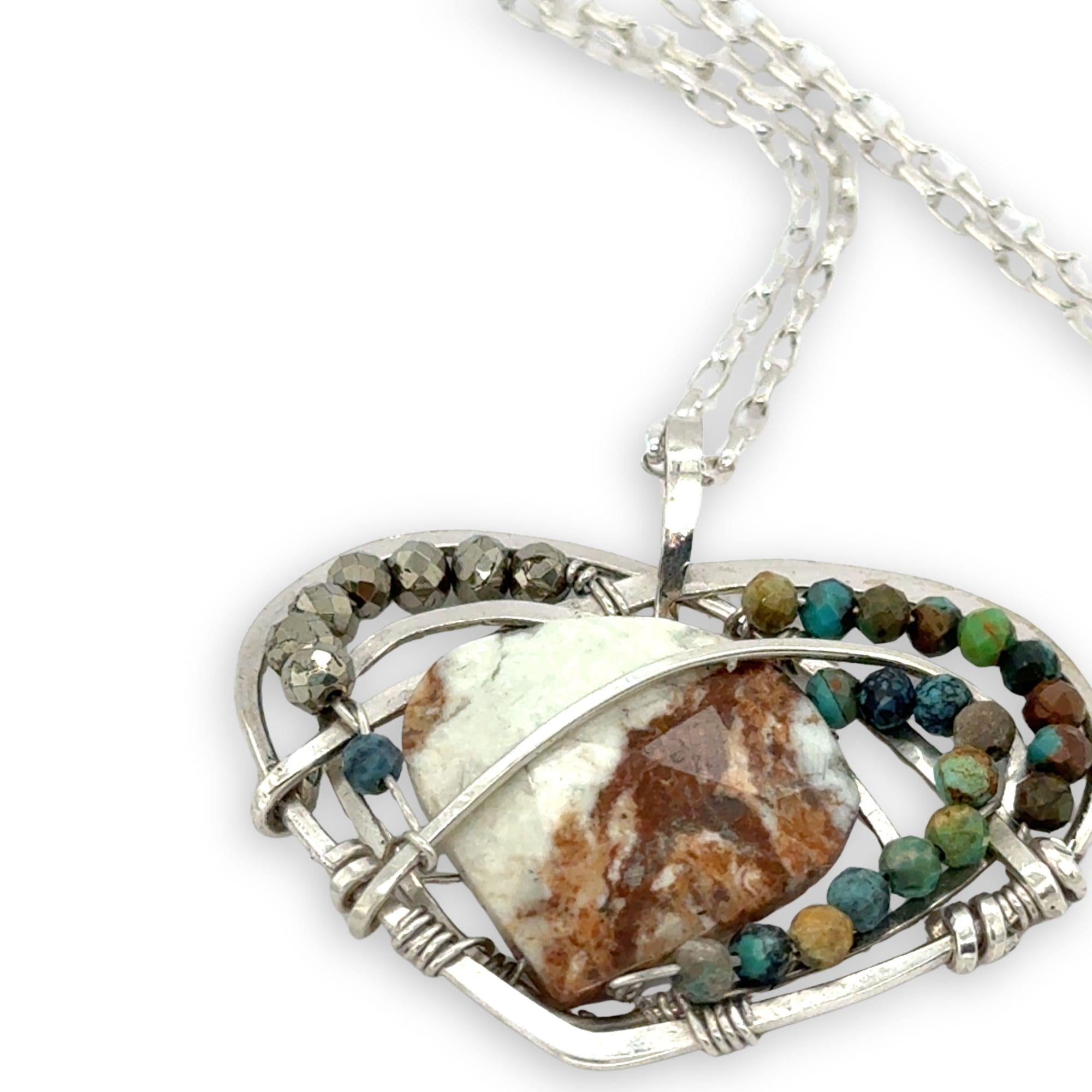Necklace with a heart-shaped sterling silver hammered pendant featuring a gaspeite, turquoise, and pyrite gemstones
