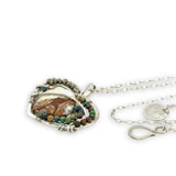 Necklace with a heart-shaped sterling silver hammered pendant featuring a gaspeite, turquoise, and pyrite gemstones