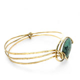 a turquoise smooth coin gemstone set in a hammered brass cuff bracelet, featuring a hand-formed clasp.