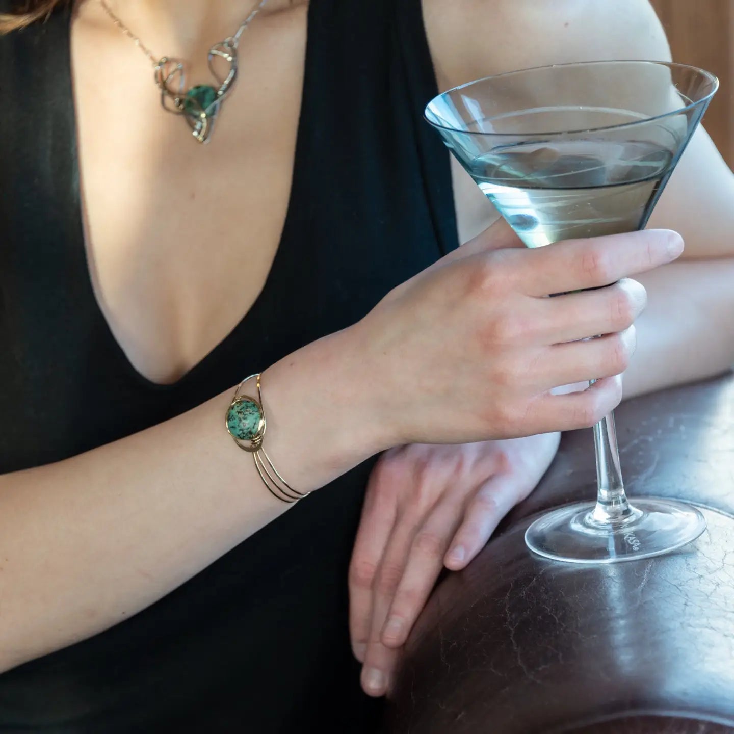 a turquoise smooth coin gemstone set in a hammered brass cuff bracelet, featuring a hand-formed clasp.