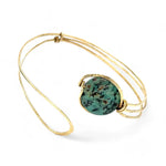 a turquoise smooth coin gemstone set in a hammered brass cuff bracelet, featuring a hand-formed clasp.