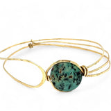 a turquoise smooth coin gemstone set in a hammered brass cuff bracelet, featuring a hand-formed clasp.