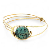a turquoise smooth coin gemstone set in a hammered brass cuff bracelet, featuring a hand-formed clasp.
