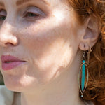 A pair of sterling silver skinny marquise earrings with turquoise stalactite on brass wire with bright blue crystal accent