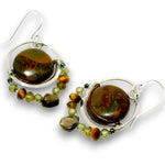 A pair of silver dangle earrings featuring polished brown jasper stones, small green beads, and tiger's eye accents, set against a plain white background.