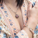 A sterling silver mini cameo pendant necklace with a salmon rhodochrosite center, wrapped in gold filled, surrounded by tourmalinated quartz gemstones. The necklace has an oxidized textured chain with hand made chain links.