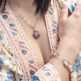 A sterling silver mini cameo pendant necklace with a salmon rhodochrosite center, wrapped in gold filled, surrounded by tourmalinated quartz gemstones. The necklace has an oxidized textured chain with hand made chain links.