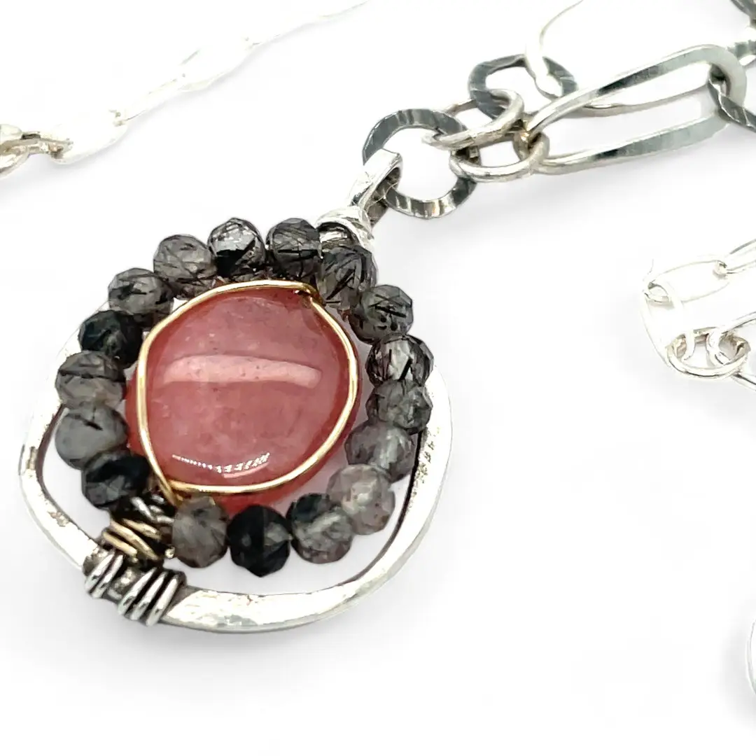 A sterling silver mini cameo pendant necklace with a salmon rhodochrosite center, wrapped in gold filled, surrounded by tourmalinated quartz gemstones. The necklace has an oxidized textured chain with hand made chain links.