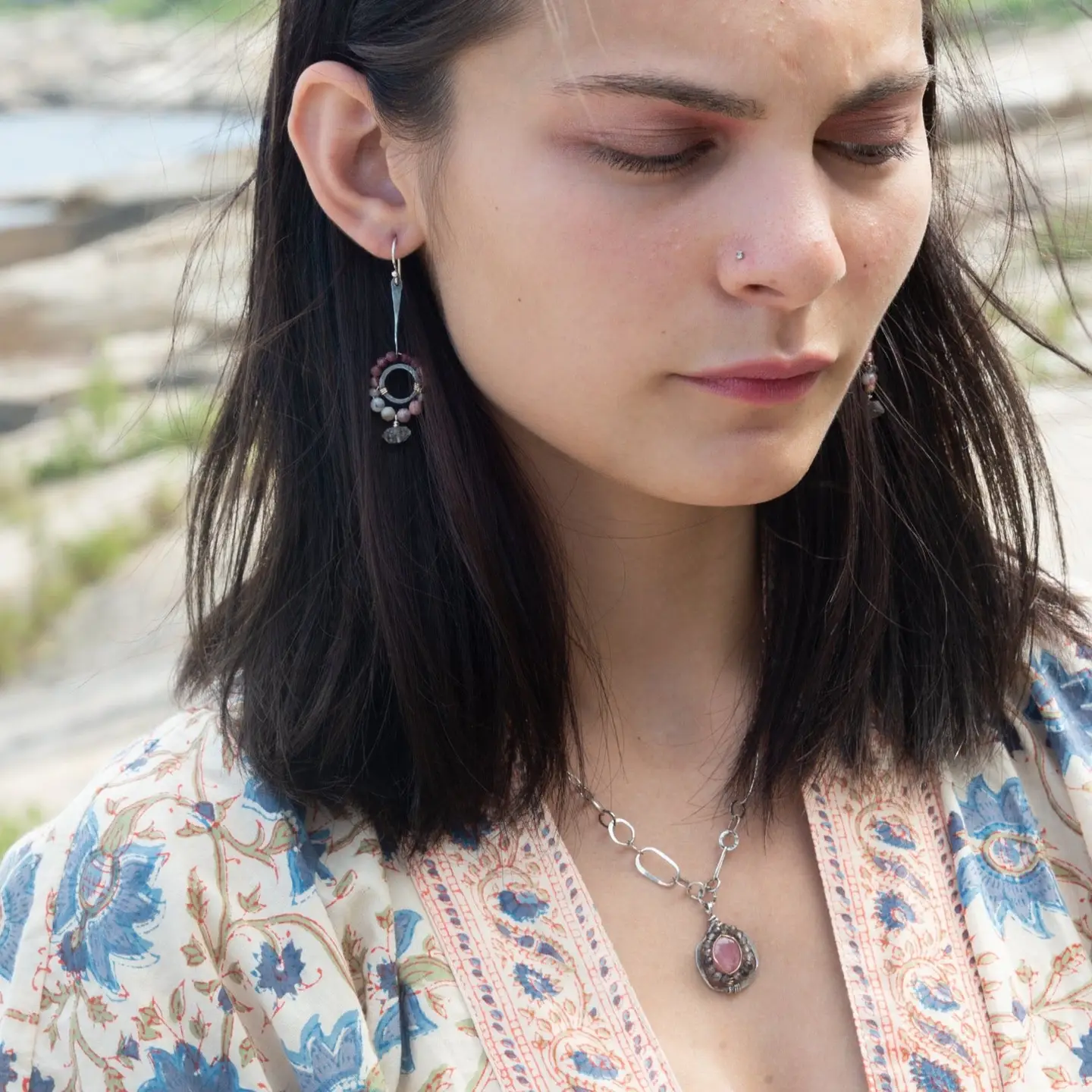 A sterling silver mini cameo pendant necklace with a salmon rhodochrosite center, wrapped in gold filled, surrounded by tourmalinated quartz gemstones. The necklace has an oxidized textured chain with hand made chain links.