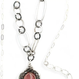 A sterling silver mini cameo pendant necklace with a salmon rhodochrosite center, wrapped in gold filled, surrounded by tourmalinated quartz gemstones. The necklace has an oxidized textured chain with hand made chain links.