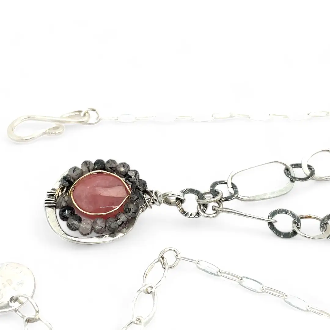 A sterling silver mini cameo pendant necklace with a salmon rhodochrosite center, wrapped in gold filled, surrounded by tourmalinated quartz gemstones. The necklace has an oxidized textured chain with hand made chain links.