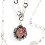 A sterling silver mini cameo pendant necklace with a salmon rhodochrosite center, wrapped in gold filled, surrounded by tourmalinated quartz gemstones. The necklace has an oxidized textured chain with hand made chain links.
