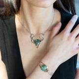 A turquoise coin gemstone sits in a hammered brass and sterling silver oxidized necklace on sterling silver bar chain