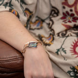 A large blue crystal is nestled within layers of braided hammered sterling silver, brass, and bronze wires to form a handmade statement cuff braceletv