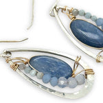 Sterling silver hammered drop earrings with smooth kyanite oval gemstones wrapped in gold fill wire surrounded by blue crystal, mini cat's eye, and blue lace agate gemstones