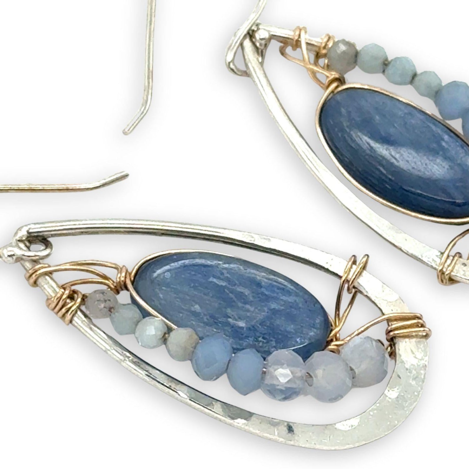 Sterling silver hammered drop earrings with smooth kyanite oval gemstones wrapped in gold fill wire surrounded by blue crystal, mini cat's eye, and blue lace agate gemstones