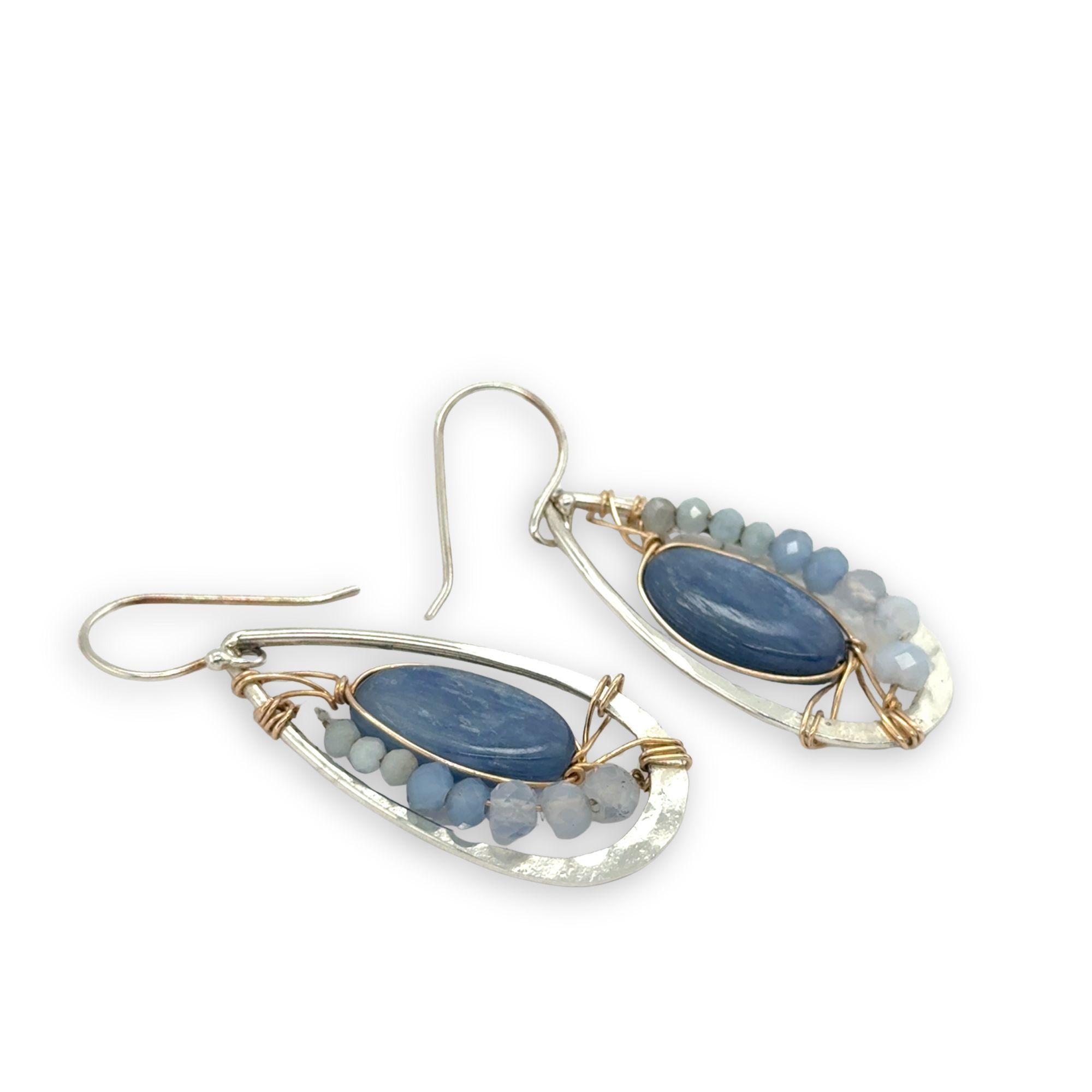Sterling silver hammered drop earrings with smooth kyanite oval gemstones wrapped in gold fill wire surrounded by blue crystal, mini cat's eye, and blue lace agate gemstones
