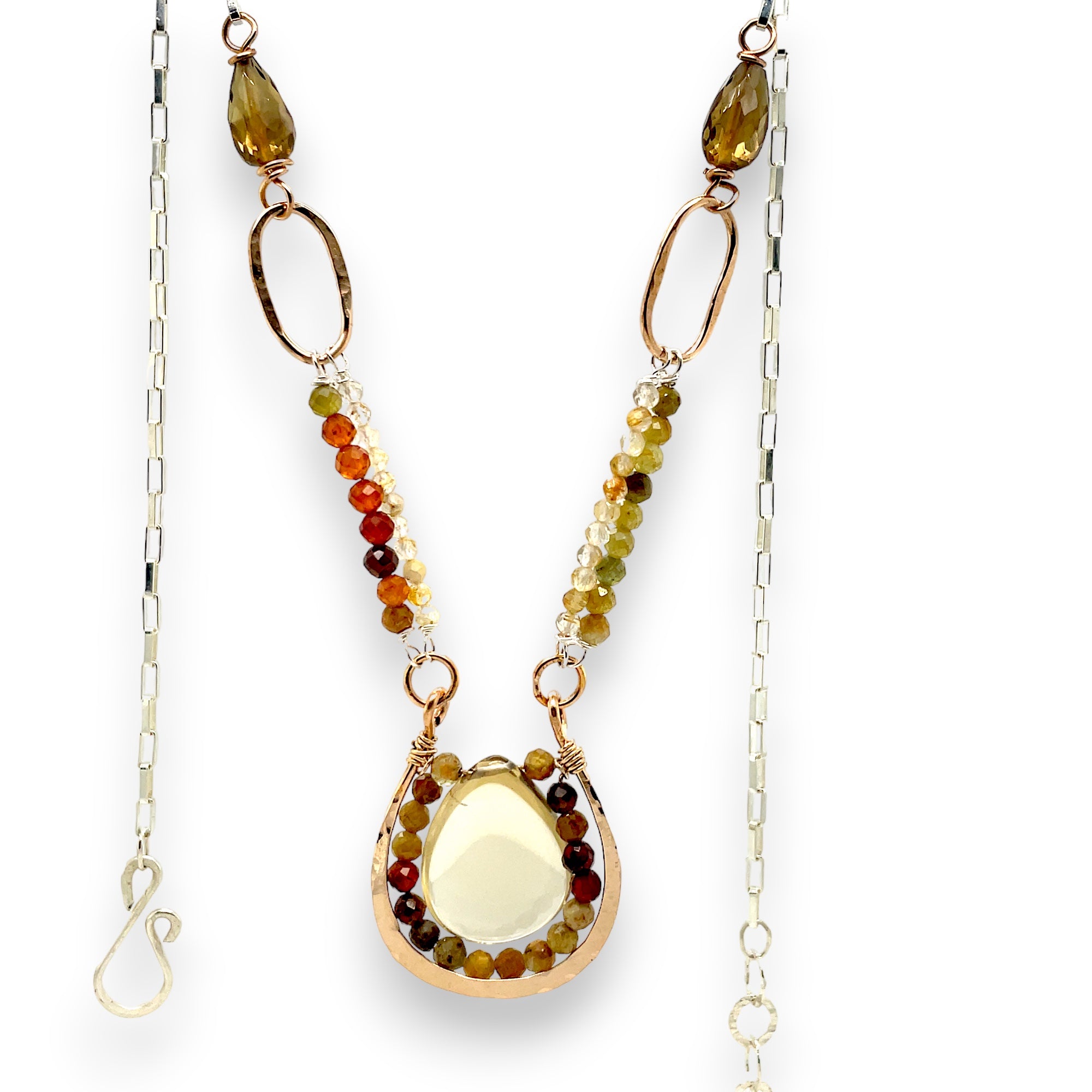 A necklace with hammered bronze links and pendant holding a smooth drop bear quartz surrounded in hessonite ombre gemstones, accented with rutilated quartz and smokey quartz gemstones within the chain