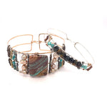 A wide bronze cuff bracelet featuring a combination of striped jasper, fresh water pearls, pyrite, smokey quartz, and turquoise gemstones, strung on sterling silver and hammered bronze.
