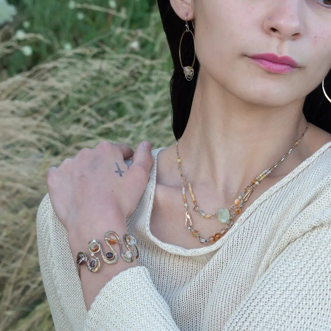 Banded brown/orange agate faceted coins are wrapped in sterling silver and gold filled wires attached to a winding river of brass hammered wire bracelet stamped with trees