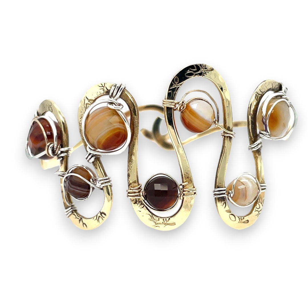Banded brown/orange agate faceted coins are wrapped in sterling silver and gold filled wires attached to a winding river of brass hammered wire bracelet stamped with trees