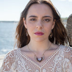 A moonstone and faceted garnet gemstones encrust wings of brass and sterling silver necklace with a gold filled chain and a signature clasp.