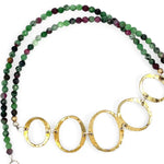 Handmade hammered brass oval rings varying in size hanging from faceted ruby zoisite gemstone necklace