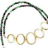Handmade hammered brass oval rings varying in size hanging from faceted ruby zoisite gemstone necklace
