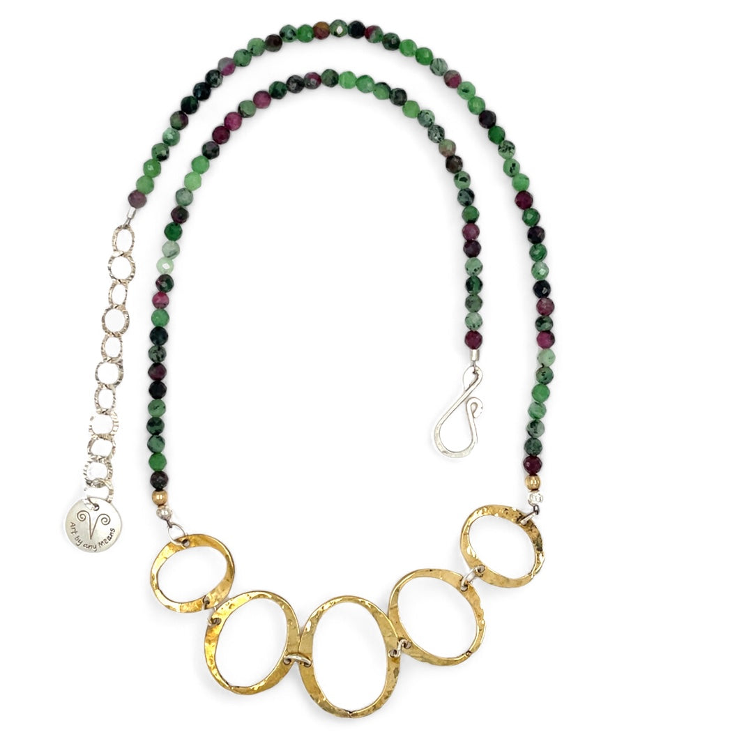 Handmade hammered brass oval rings varying in size hanging from faceted ruby zoisite gemstone necklace