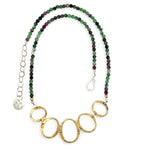 Handmade hammered brass oval rings varying in size hanging from faceted ruby zoisite gemstone necklace