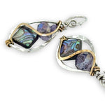 Pair of earrings with purple crystals and abalone gemstones and silver and gold accents on a white background