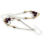 Gold and silver earrings with garnet gemstone beads on a white background