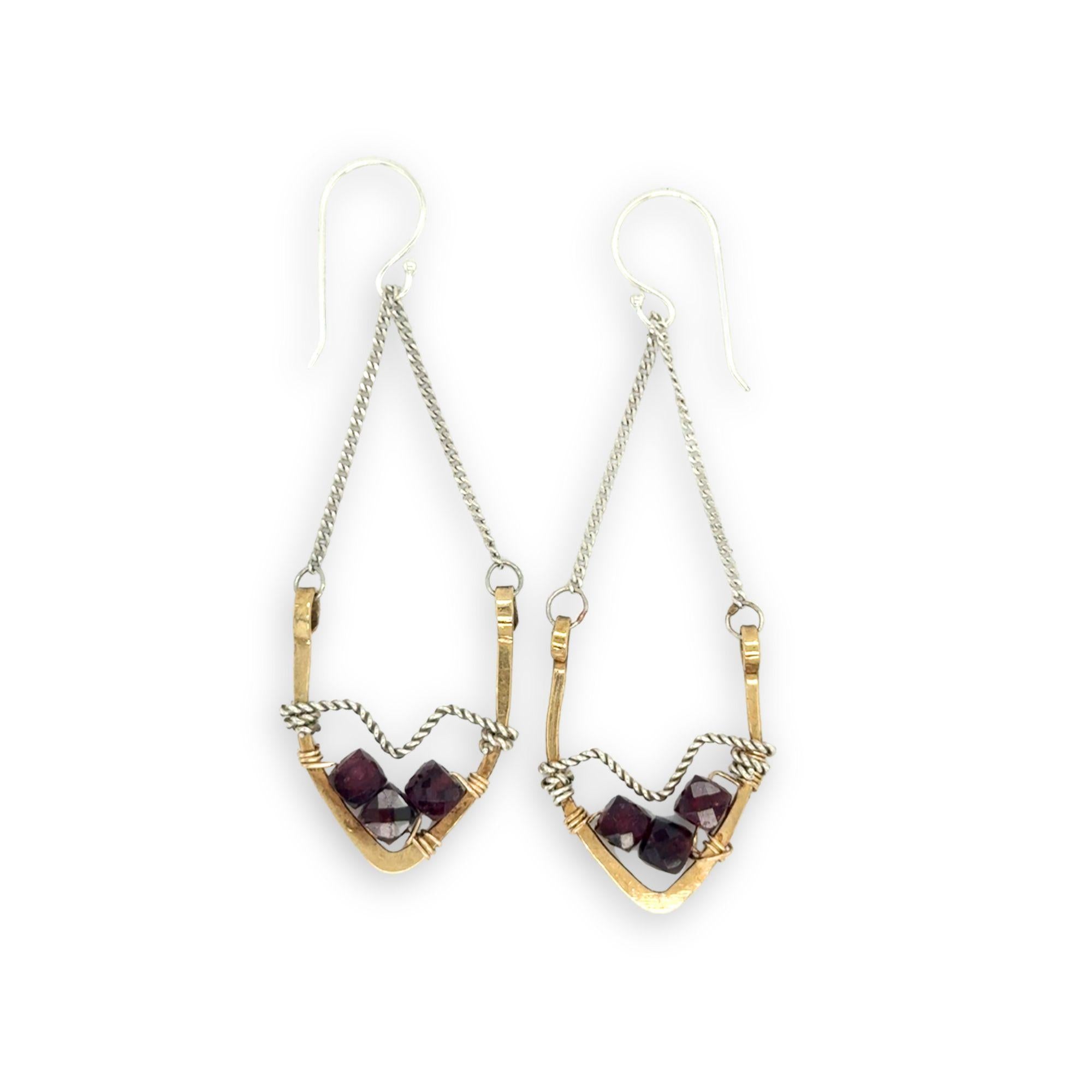 Pair of earrings with geometric design and garnet gemstones on a white background