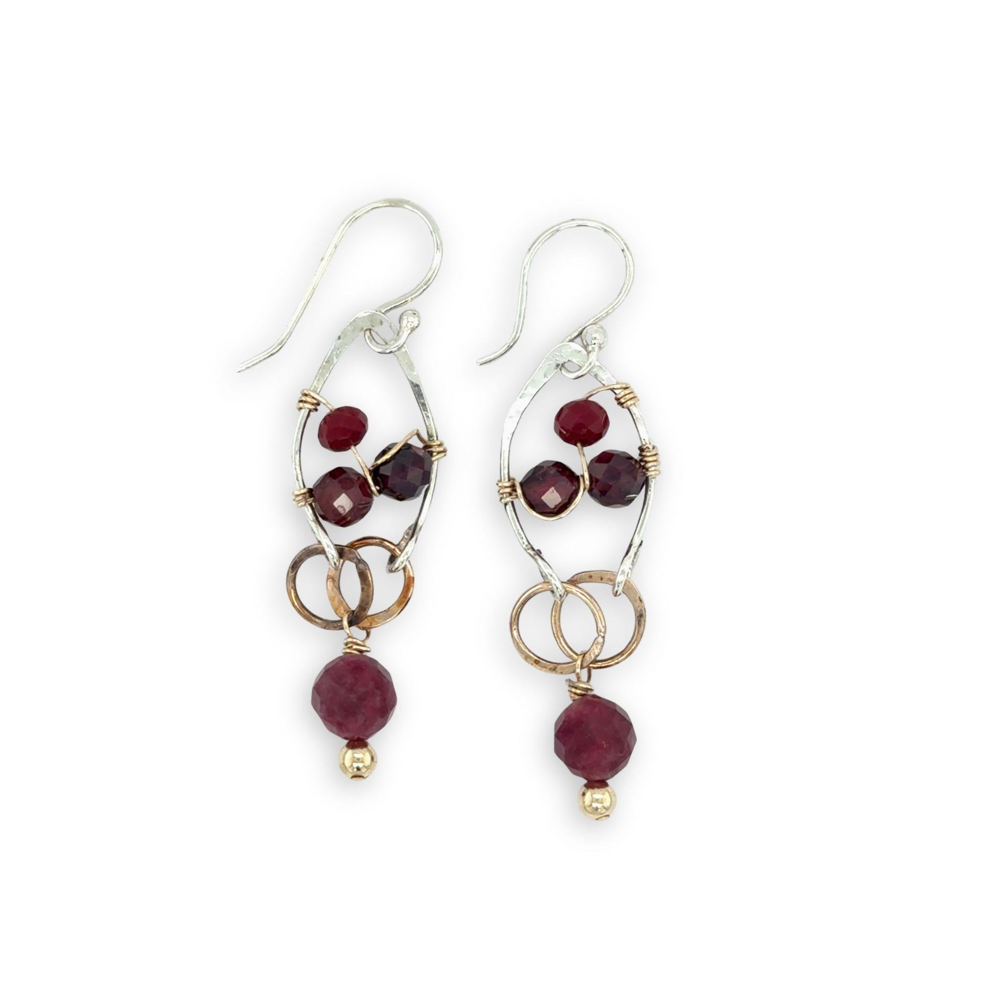 Pair of earrings with garnet gemstone beads and gold accents on a white background