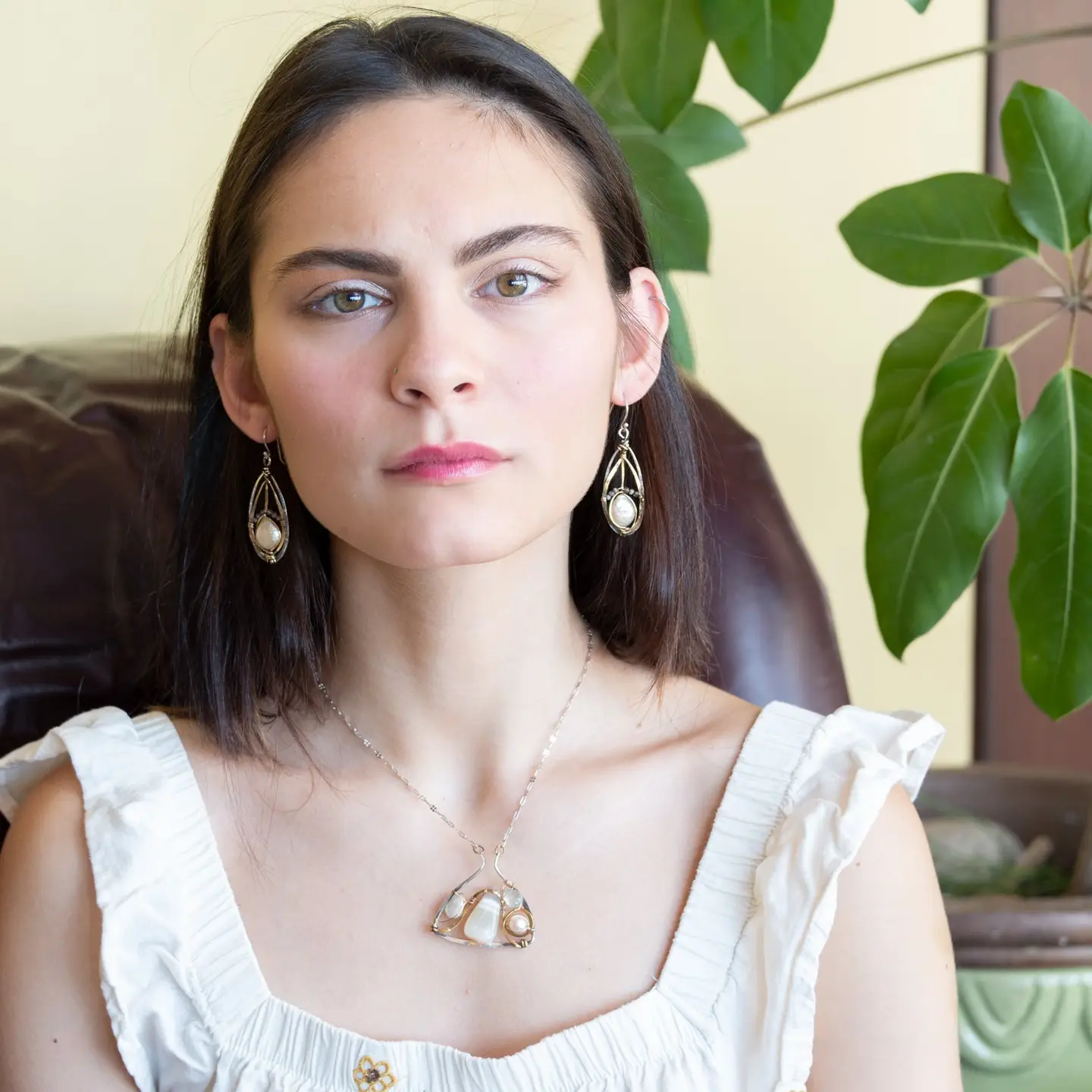 Woman wearing earrings and a necklace with a neutral background