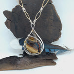 Petrified wood, smokey quartz, and tiger's eye gemstones fill a sterling silver pendant necklace with gold fill accents