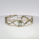 neutral green colored faceted crystals held in braided layers of sterling silver, bronze and twisted brass hammered wires all inside a bronze cuff handmade bracelet