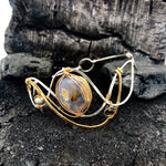 light purple chalcedony smooth nugget surrounded by layers of hammered sterling silver and brass wires to form a statement bracelet accented with fresh water pearl and crystal