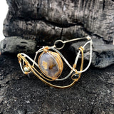 light purple chalcedony smooth nugget surrounded by layers of hammered sterling silver and brass wires to form a statement bracelet accented with fresh water pearl and crystal