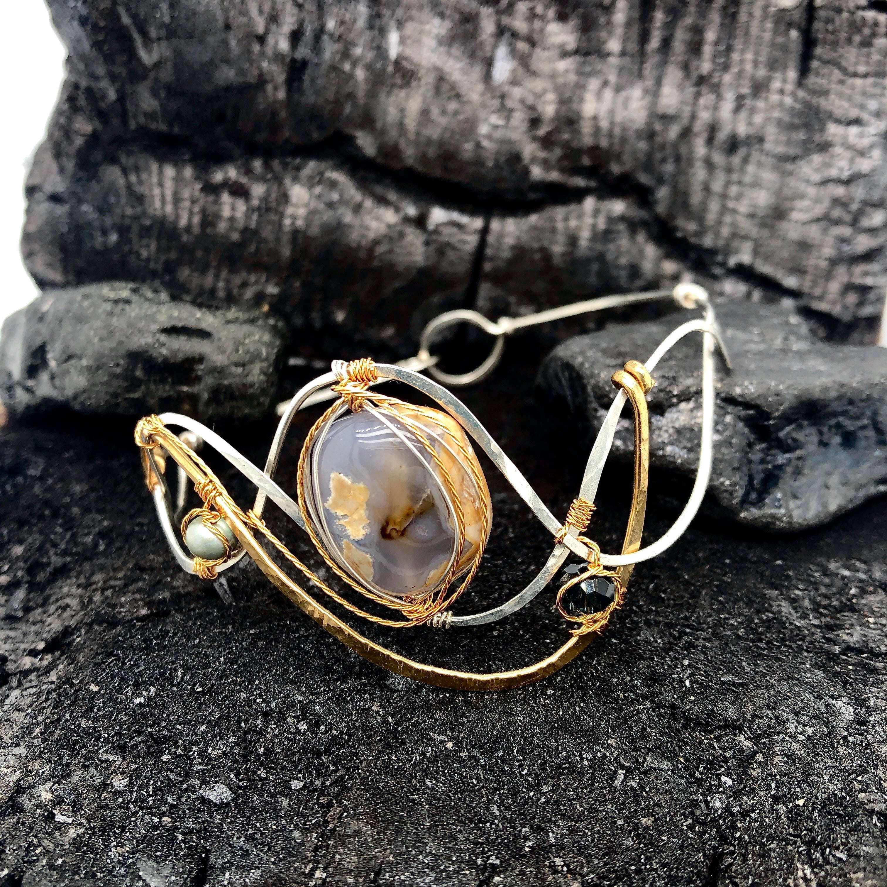 light purple chalcedony smooth nugget surrounded by layers of hammered sterling silver and brass wires to form a statement bracelet accented with fresh water pearl and crystal