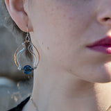 A bronze hoop earring with sparkly sterling silver and oxidized twisted sterling silver swishes holding a blue kyanite stone.
