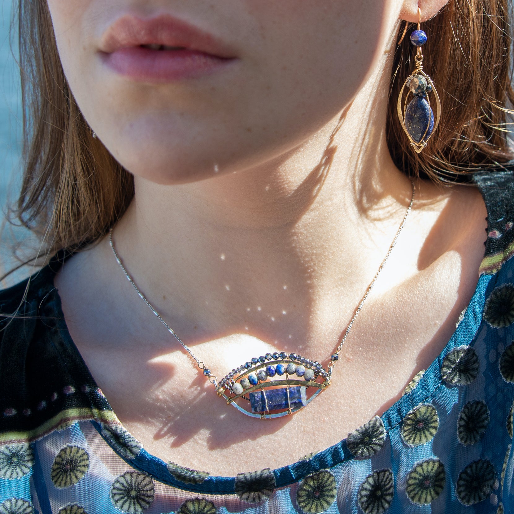 Lapis rectangle set into a sterling silver and brass blue jay pendant on a sparkly sterling silver dash chain. Accented with blue quartz, pyrite, and lapis gemstones held on with gold filled wire