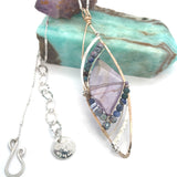 A necklace with a bronze marquise pendant featuring a ametyst center stone encrusted with ruby zoisite, fresh water pearl, and sodalite gemstones with sterling silver wire accent