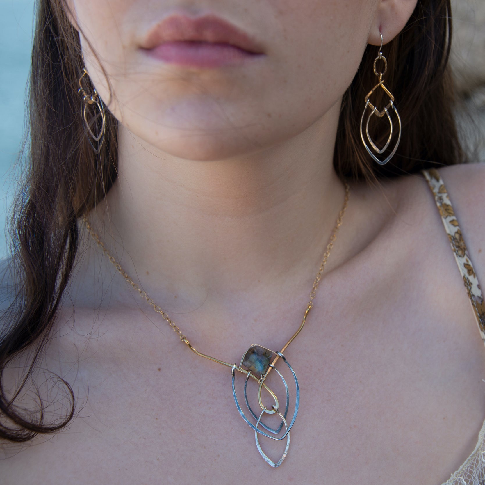 Sterling silver double teardrops swinging from stamped brass diamonds, all hanging from a braided brass link