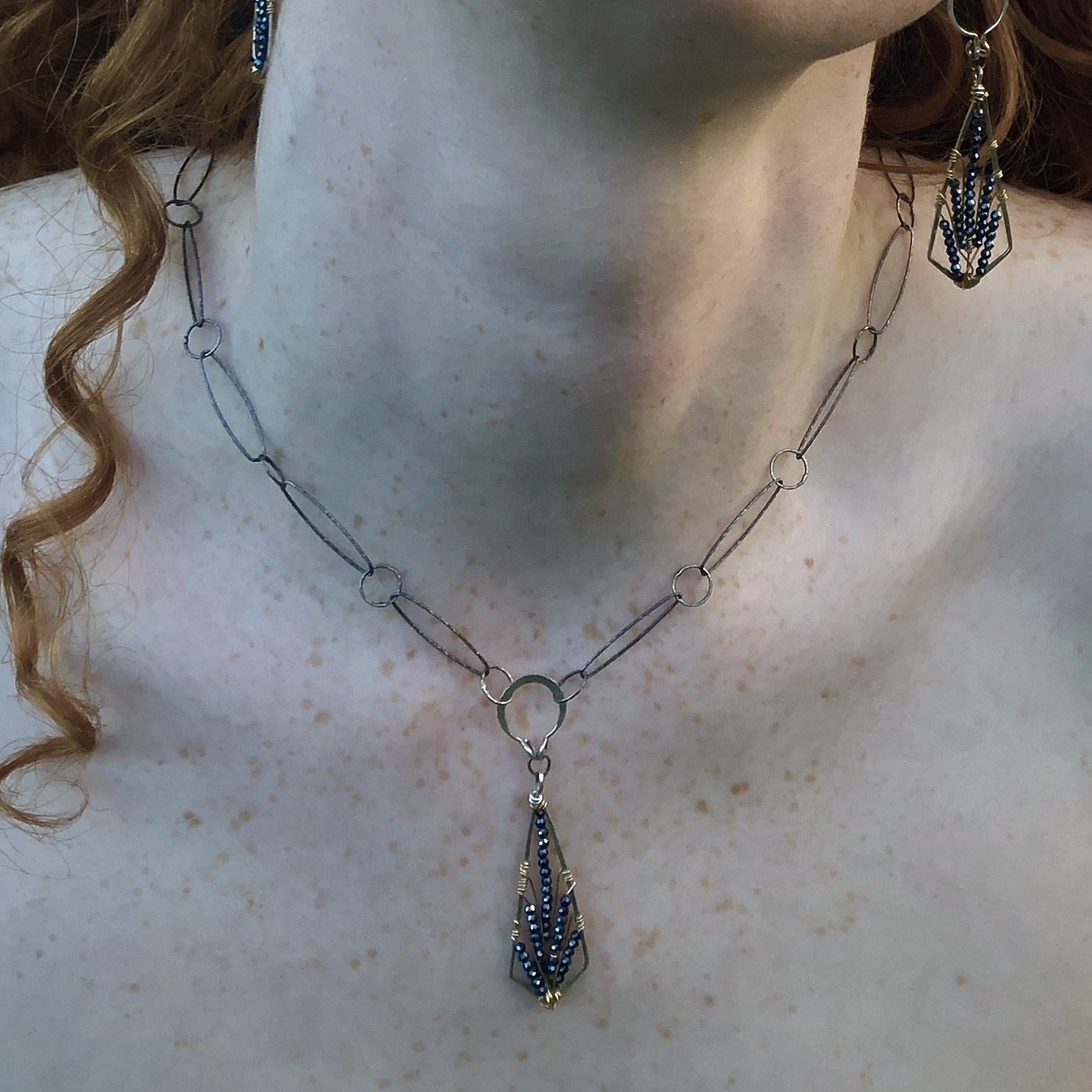 Sterling silver point necklace with black spinel gemstones woven on gold filled wire onto a darkened sterling silver diamond cut link chain