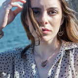 Faceted garnet gemstones braided within a sterling silver and brass fan necklace with oxidized sterling twisted wire on a delicate darkened chain